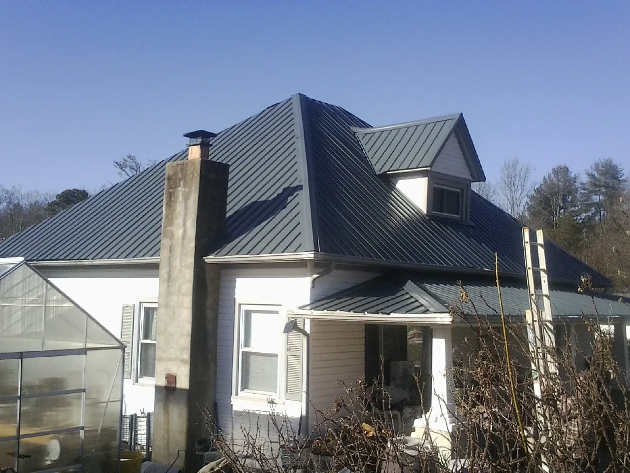 Dark blue standing seam metal roof on a white farmhouse with dormer — Slate & Tile Roof Repair by Roofing Brothers in Breinigsville