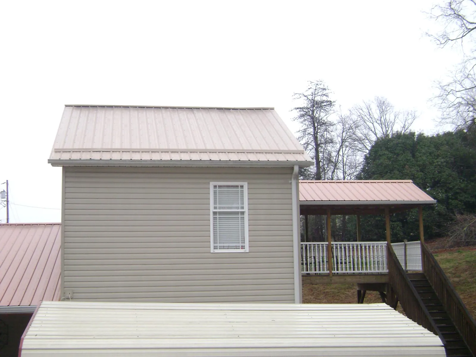 Tan metal roofs on a two story addition and attached porch, from a Roof Replacement job in Breinigsville
