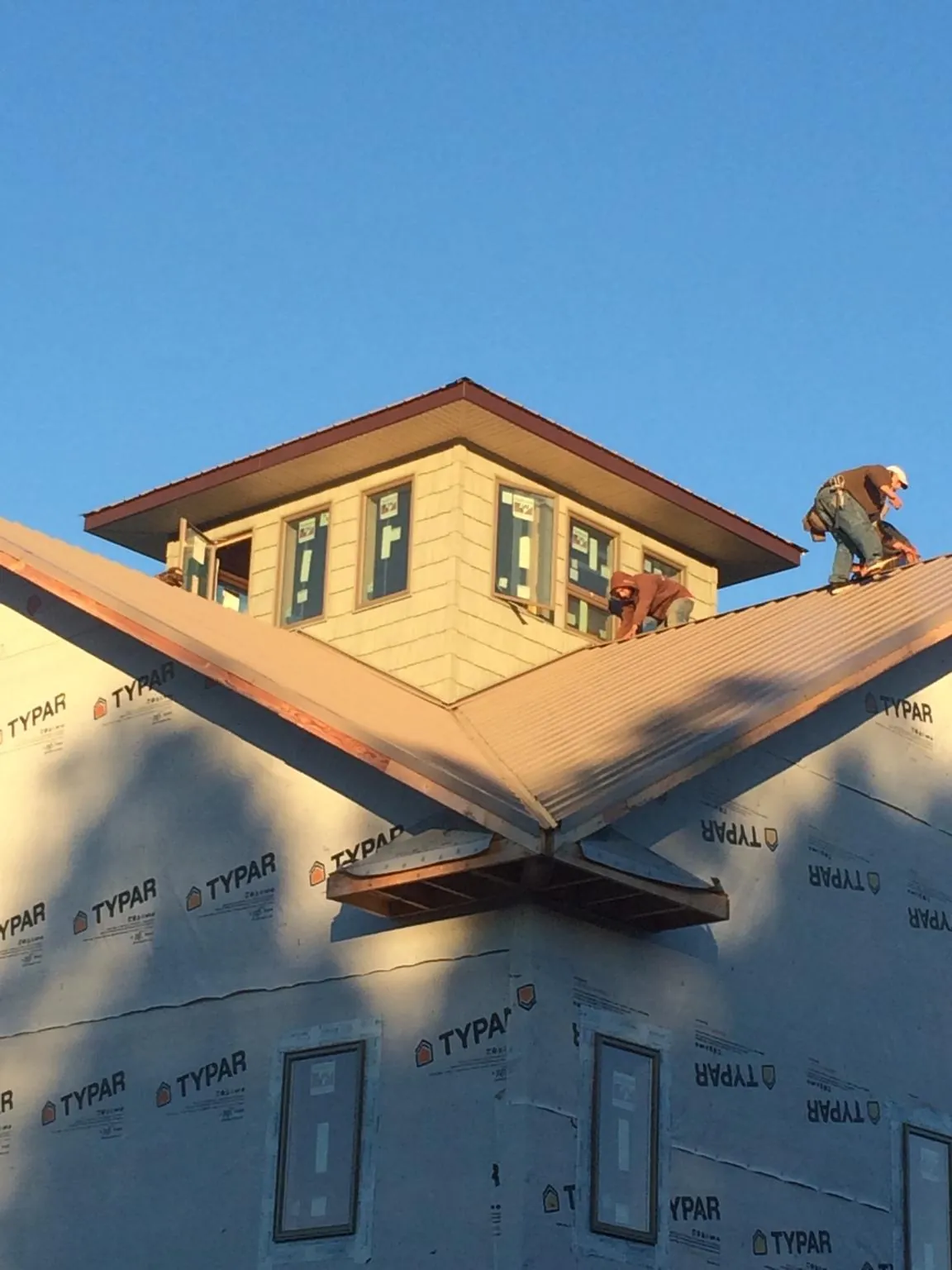 Roofers working around a rooftop cupola on a new metal roof at sunset — Roof Waterproofing in Breinigsville by Roofing Brothers
